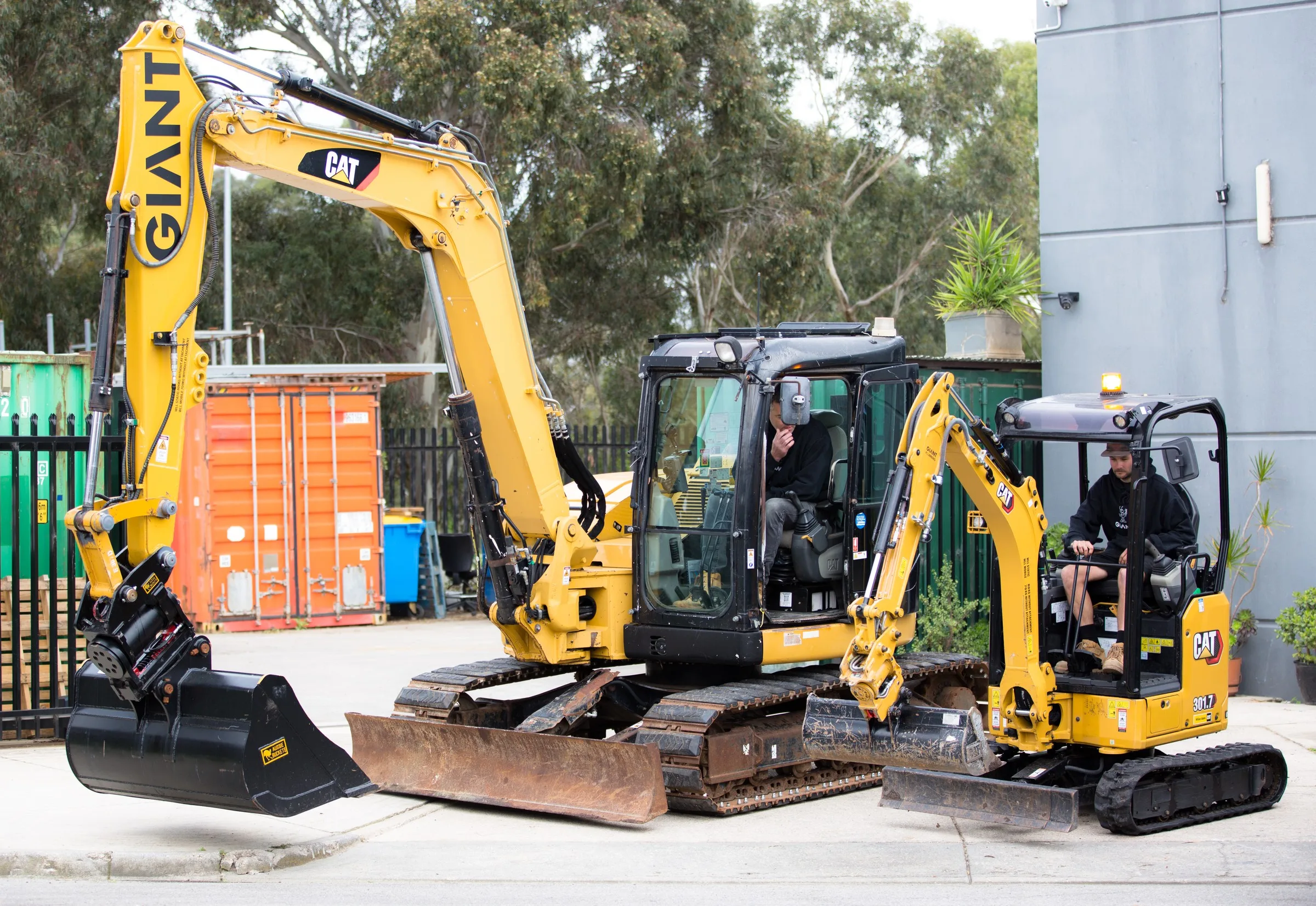 Two of Giant Plumbing's excavators at the yard, with operators in the cabs