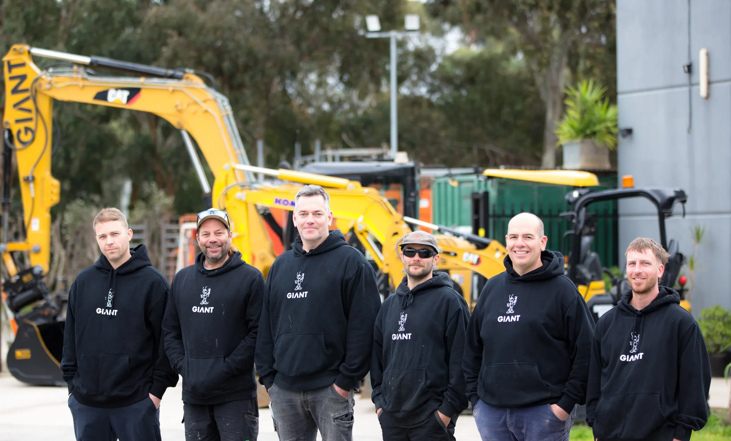 The Giant Plumbing team in front of their excavators at the yard
