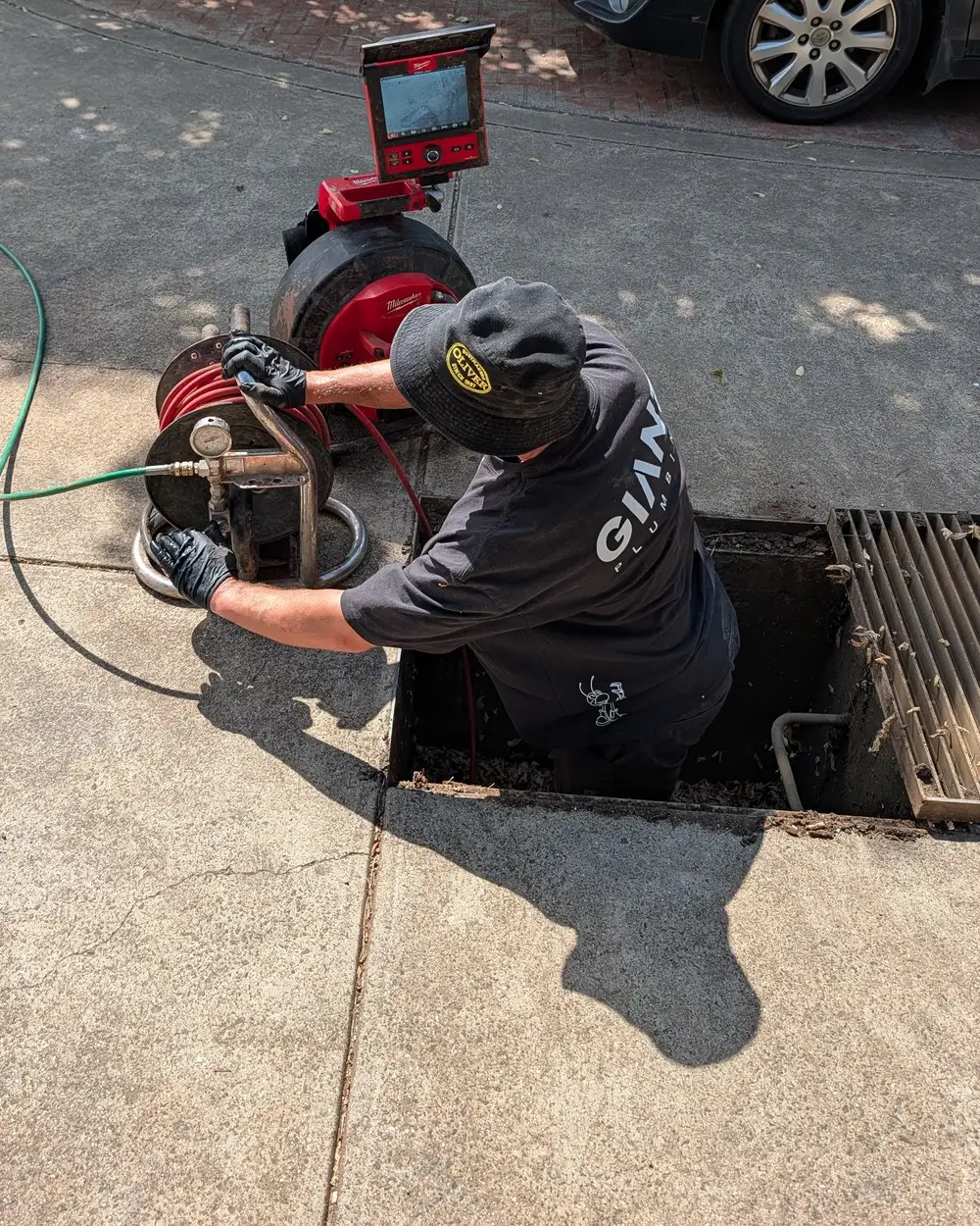 A Giant Plumbing technician feeding a drain camera into a stormwater pit