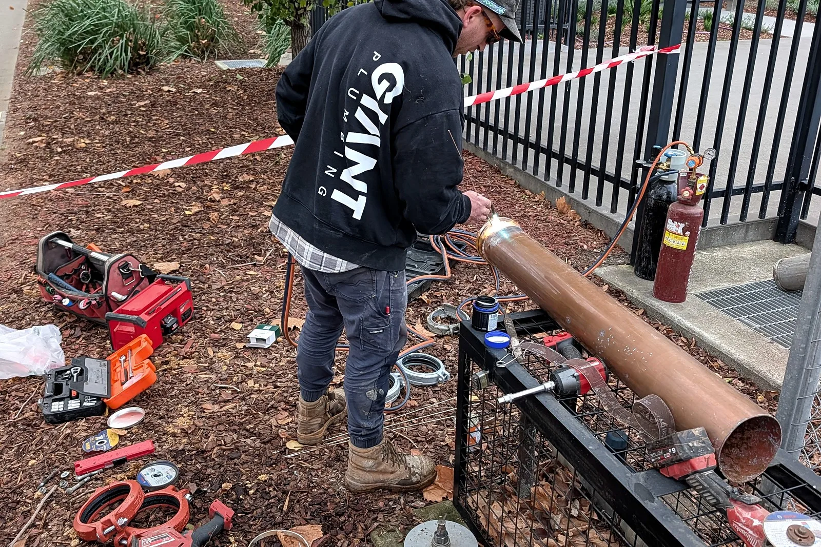 A Giant Plumbing team member works on the red pipework of a caged fire booster assembly