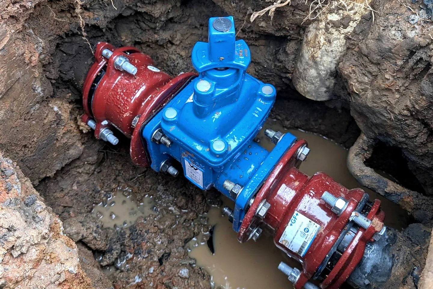 A new blue gate valve with red couplings fitted to an underground fire main in a wet pit