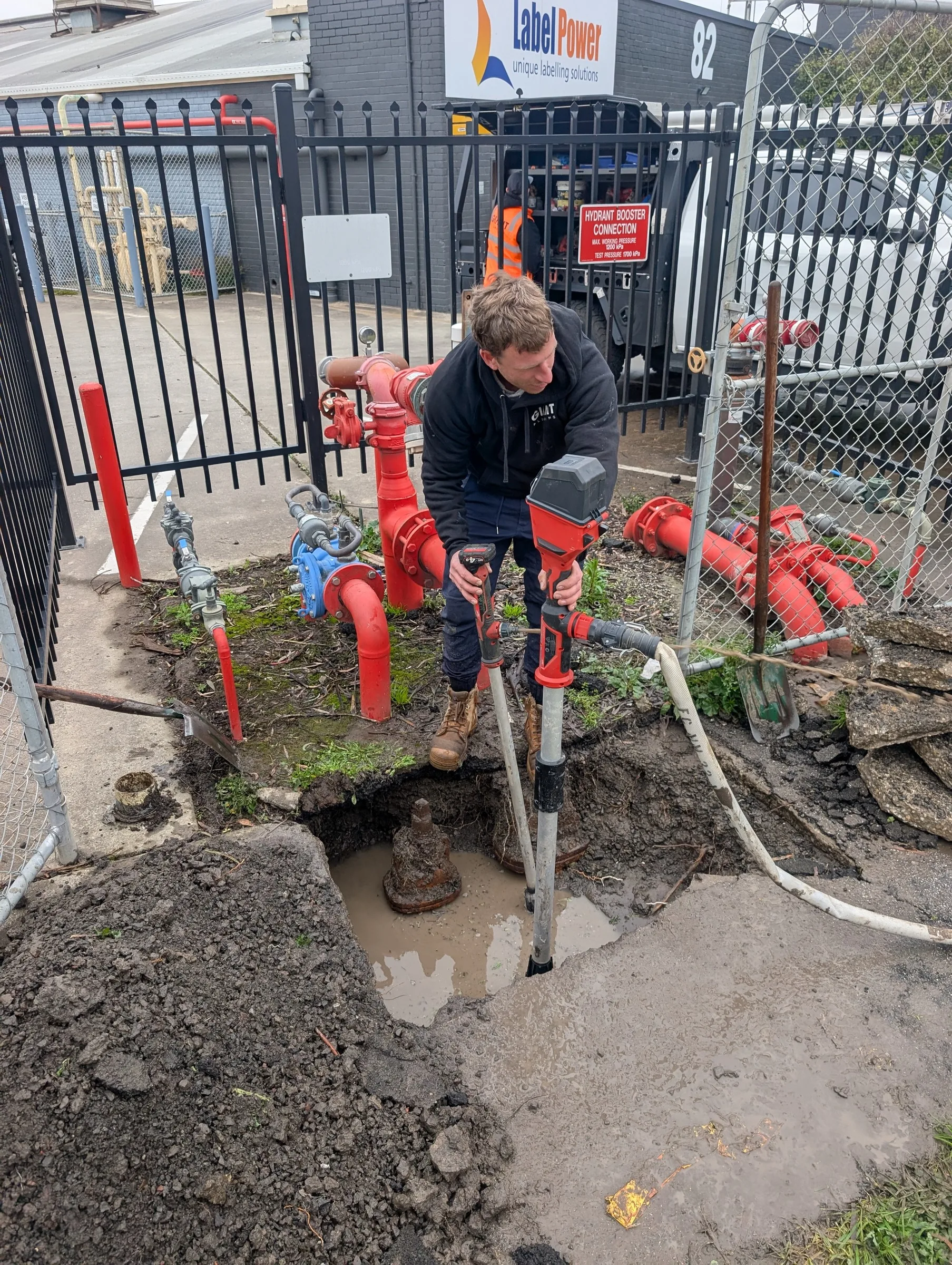 Giant Plumbing technician investigating a leak beside red fire hydrant pipework