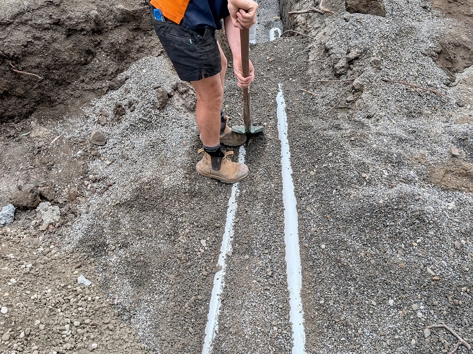 A Giant Plumbing worker marks out a long trench across a large building site