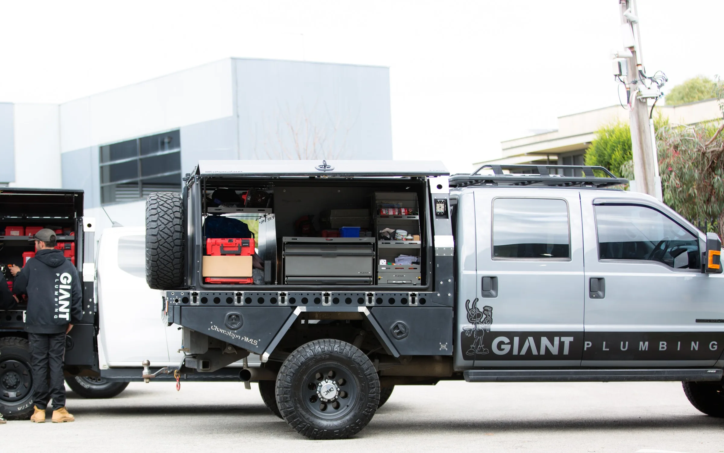 A Giant Plumbing ute with its canopy open and fitted out, two of the crew at the ute behind it