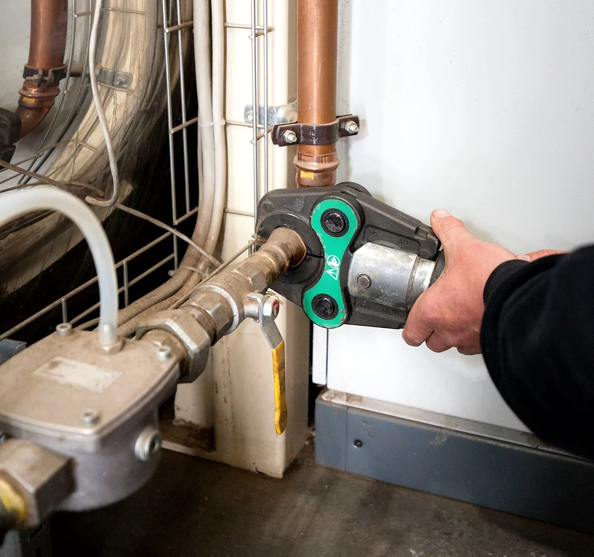 Giant Plumbing technician press-fitting copper gas pipework on an industrial burner in Melbourne