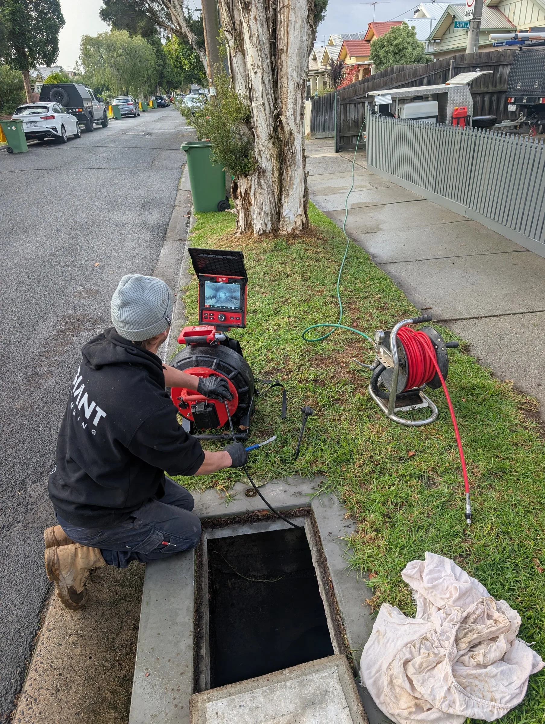 Giant Plumbing technician using a drain inspection camera on a footpath