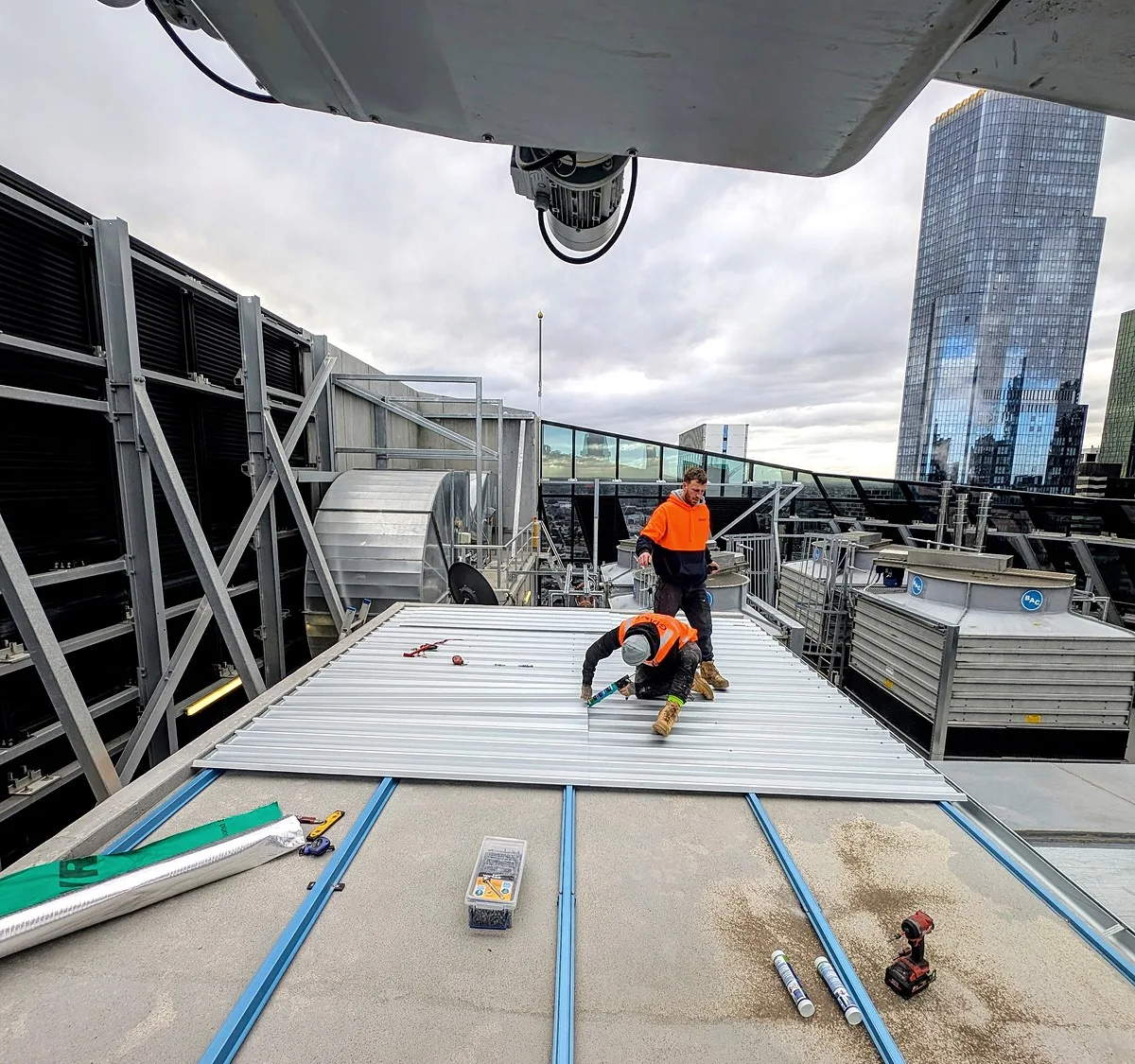 Giant Plumbing roofers fixing new metal roof sheets on a high-rise commercial building in Melbourne