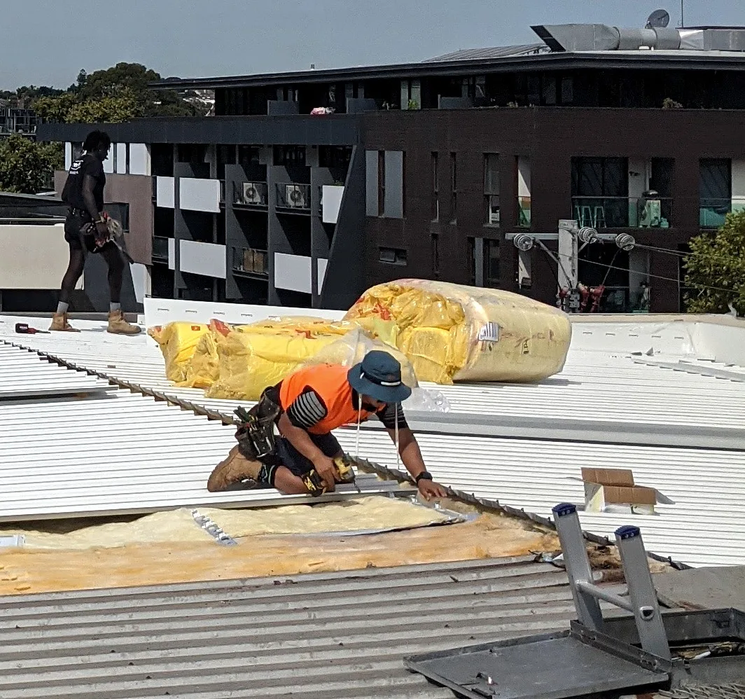 Commercial re-roof in Melbourne by Giant Plumbing, with new metal roof sheets fixed over insulation blanket